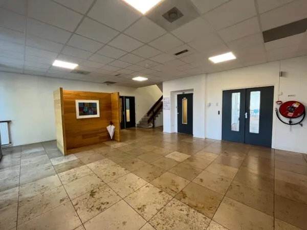 Moderne en lichte hal in een kantoorgebouw aan de Jan van Eycklaan, met marmeren vloer, houten wand met kunstwerk en dubbele deuren.